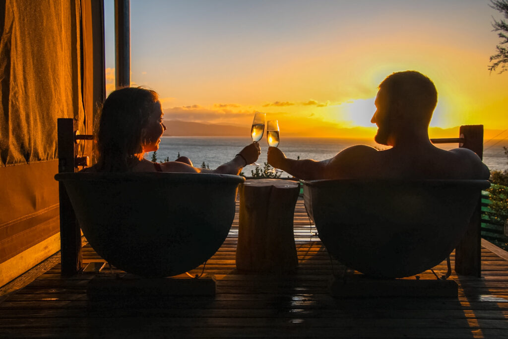 couple drinking in Outdoor Baths sunset at golden bay nz