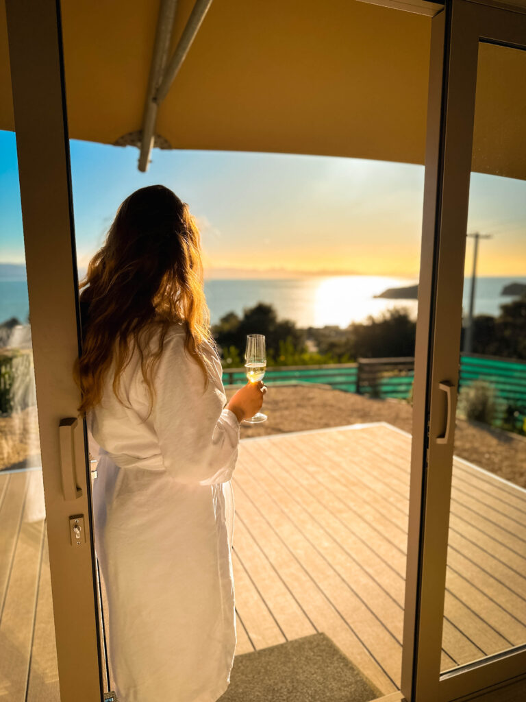 lady holding a glass at Tent Korimako Sunset view golden bay tasman nz