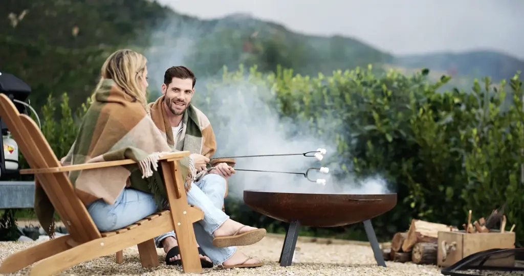 couple enjoying firepit and marshmallows at drift off grid glamping tent